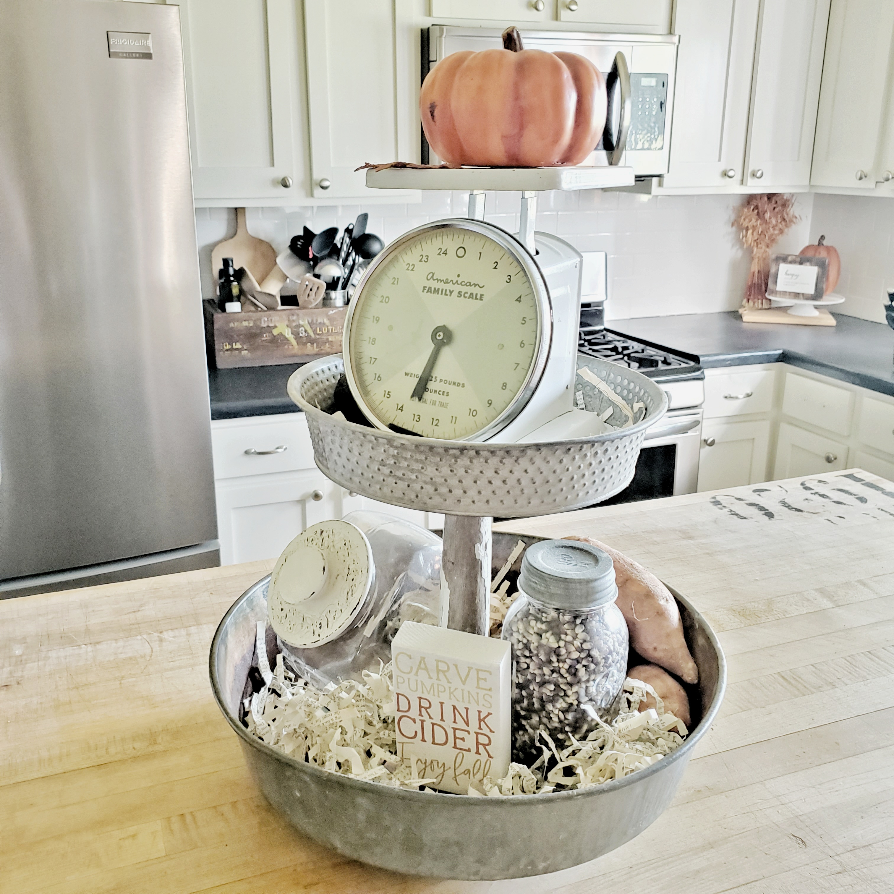 Repurposed oil pan and banister spindle tiered tray for your island.  The metal looks great against the reclaimed butcher block countertop.  Filled with fresh produce and a vintage scale.