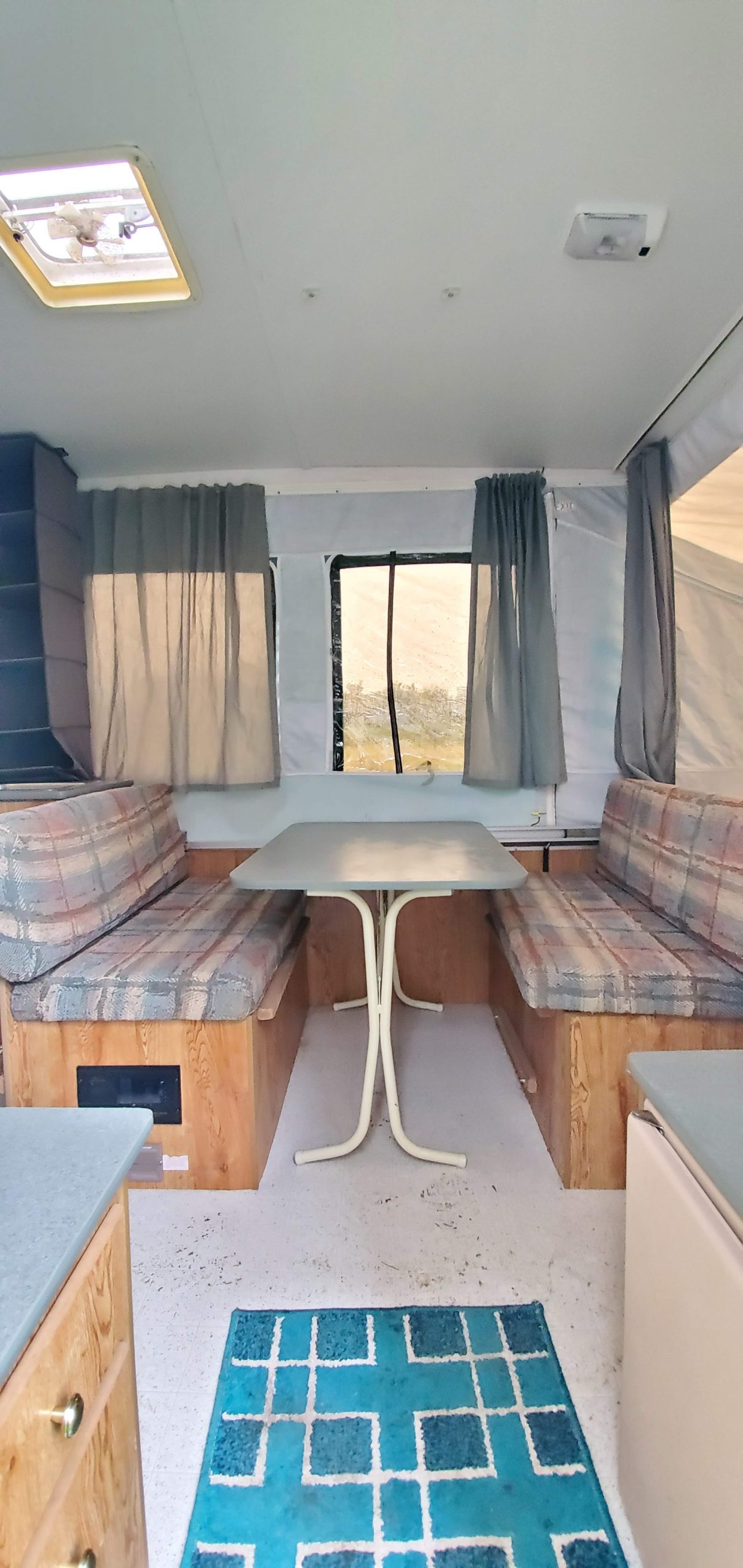 Update your RV with a modern farmhouse look with gray painted cabinets, curtains, a new wood stained table, and updated countertops for less than $500!