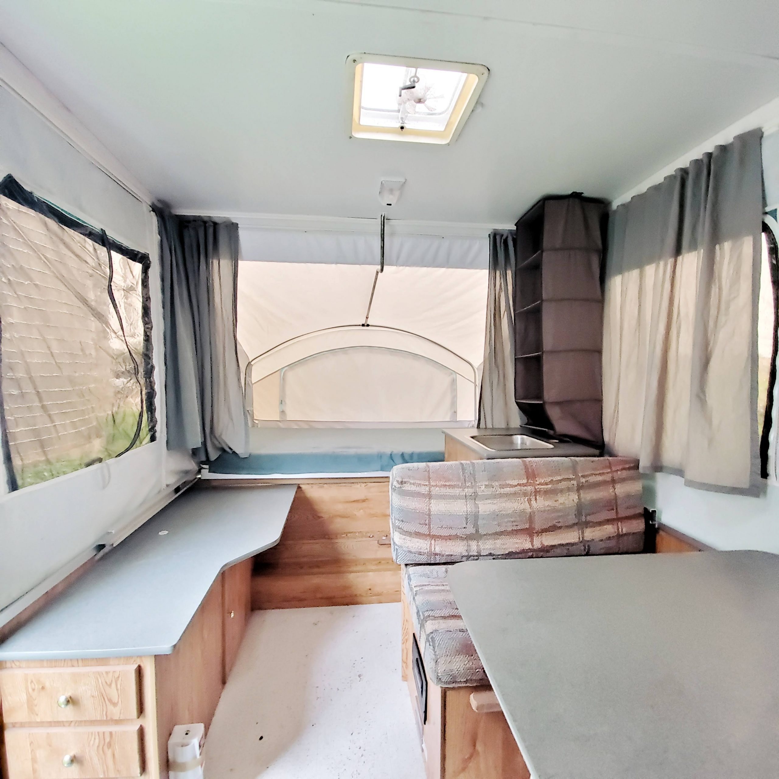 Update your RV with a modern farmhouse look with gray painted cabinets, curtains, a new wood stained table, and updated countertops for less than $500!