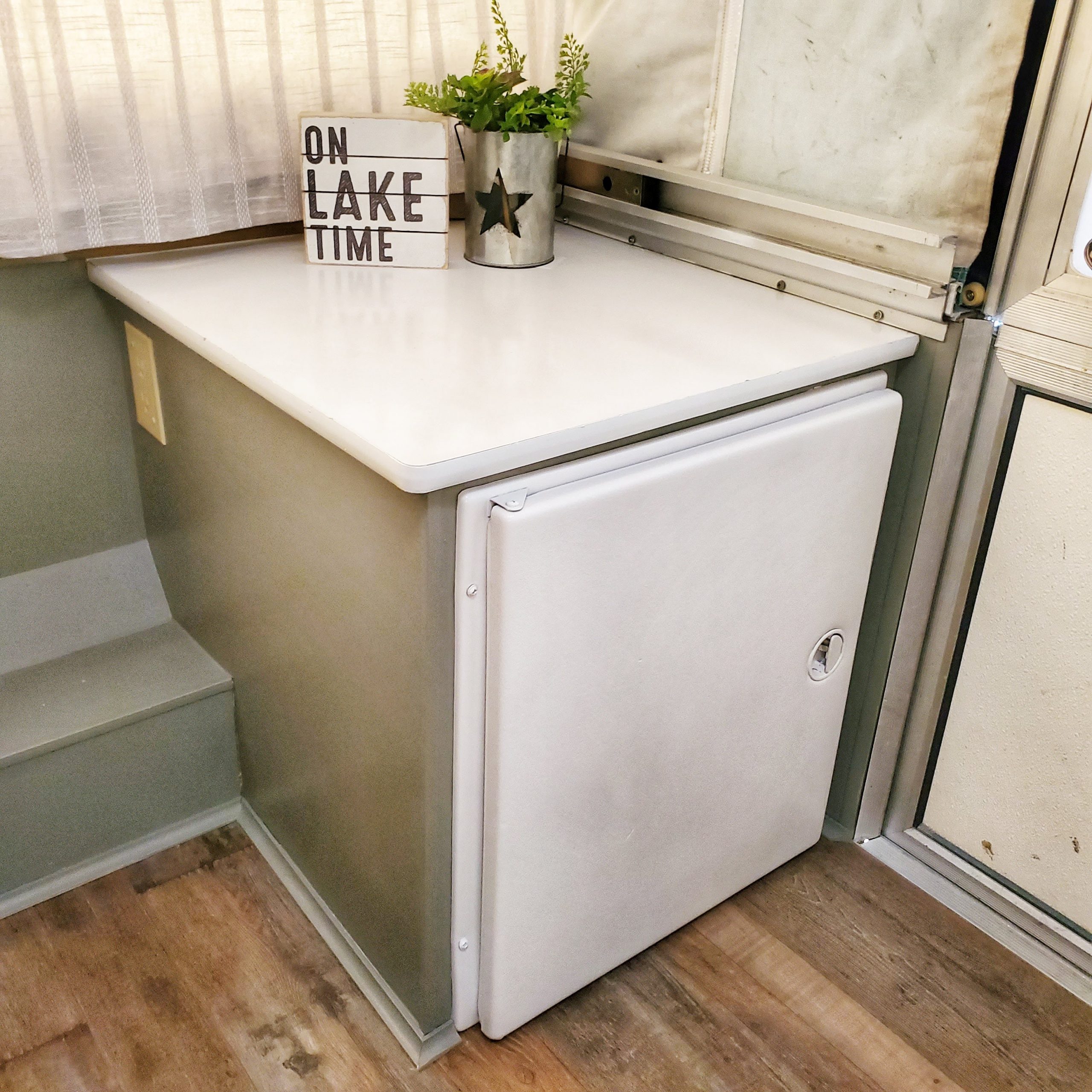 Update your RV with a modern farmhouse look with gray painted cabinets, curtains, a new wood stained table, and updated countertops for less than $500!