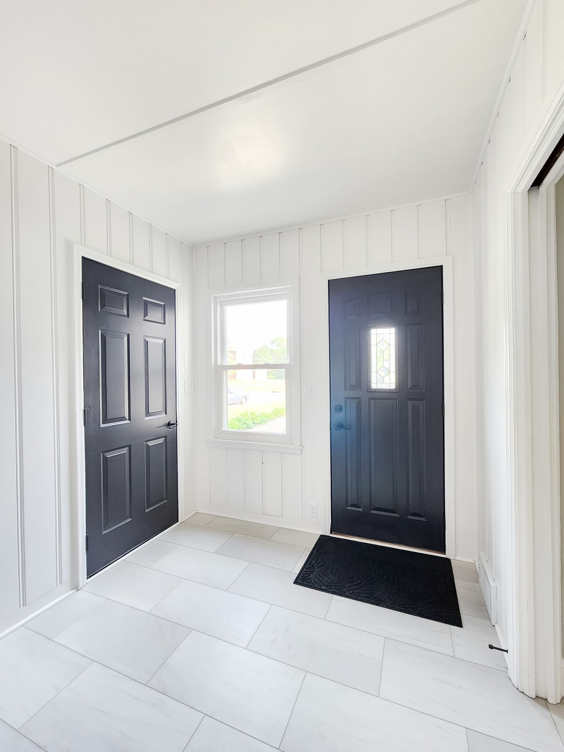 Black and white farmhouse style mudroom remodel with luxury vinyl tile flooring.